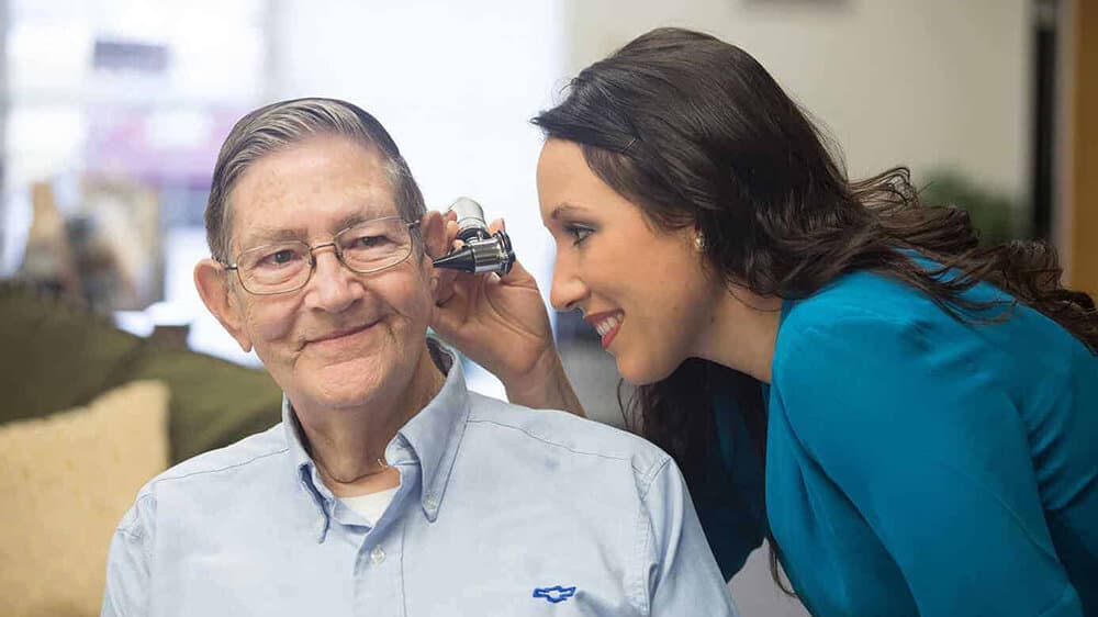 Candace Wawra, HIS performing an ear exam on elderly patient
