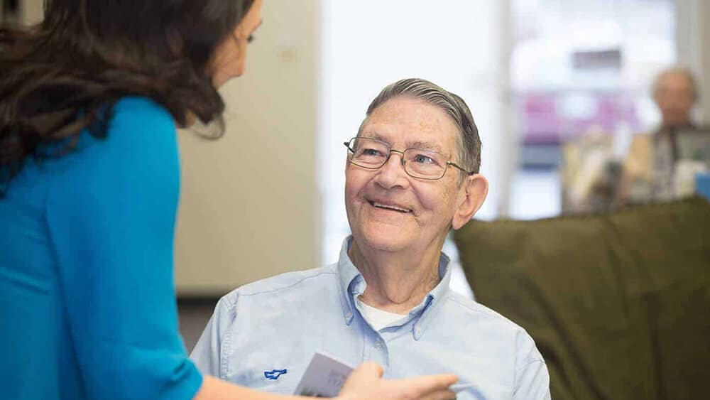 Elderly man smiling and looking up at Candace Wawra, HIS