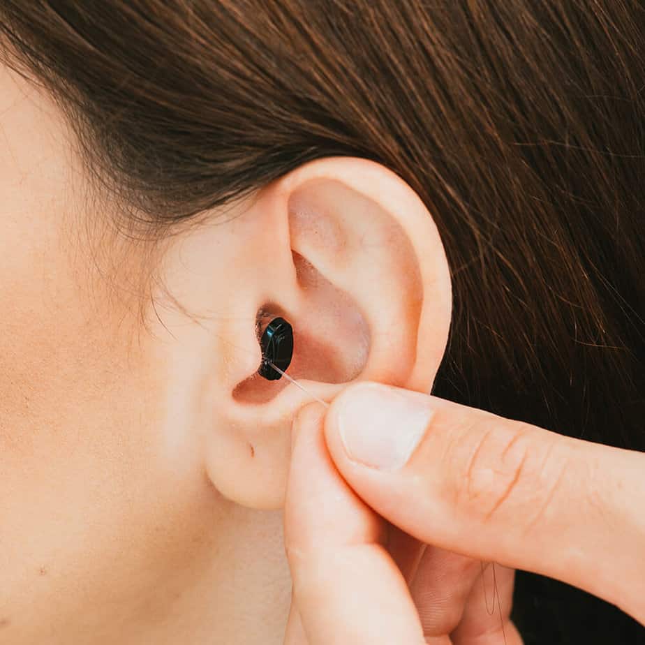 ITE hearing aid in ear being pinched by two fingers