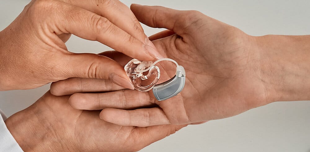 Hearing Aid Specialist placing hearing aid in patient;s hand