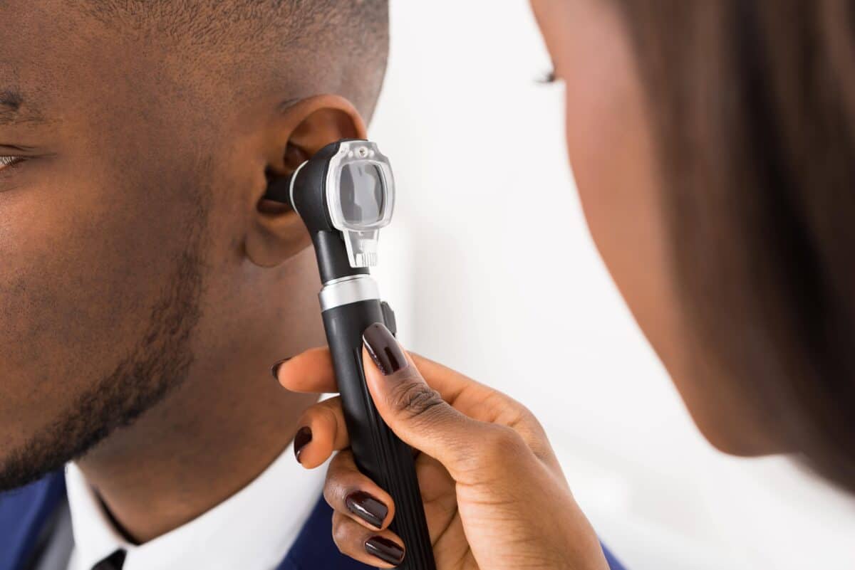 Audiologist inspecting patient's ear
