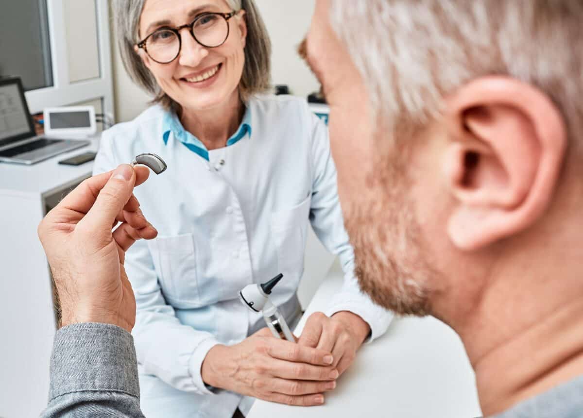 Audiologist giving patient his hearing aid